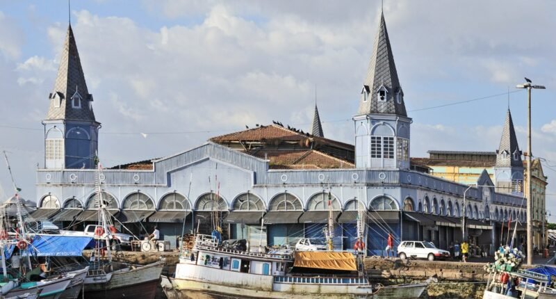 Mercado de Ferro do Ver-o-Peso, com torres pontiagudas, e barcos atracados no cais de Belém