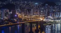 Vista noturna da Terceira Ponte iluminada, ligando Vitória a Vila Velha, com prédios ao fundo