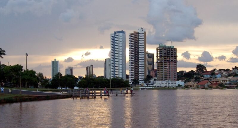 Lago do Parque das Nações Indígenas com prédios de Campo Grande ao fundo, ao entardecer