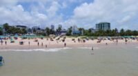 Praia de Tambaú, em João Pessoa, com banhistas na areia e prédios baixos na orla