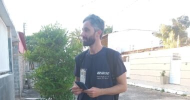Recenseador do IBGE, com colete e crachá, durante a coleta do Censo 2022