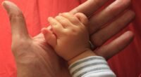 Mão de um bebê segurando o dedo de um adulto