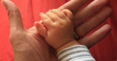 Mão de um bebê segurando o dedo de um adulto