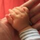 Mão de um bebê segurando o dedo de um adulto
