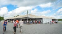 Grandes tendas brancas de acolhimento da Operação Acolhida, em Roraima, com pessoas ao longe