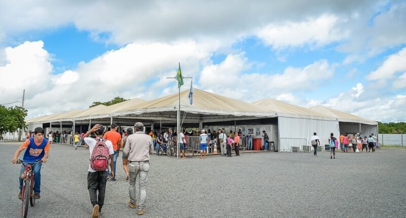 Grandes tendas brancas de acolhimento da Operação Acolhida, em Roraima, com pessoas ao longe
